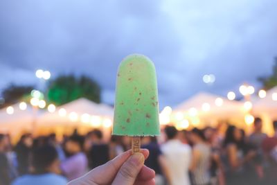 Cropped image of woman holding flavored ice at night