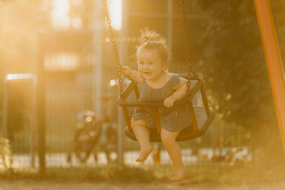 Full length of young woman swinging at playground