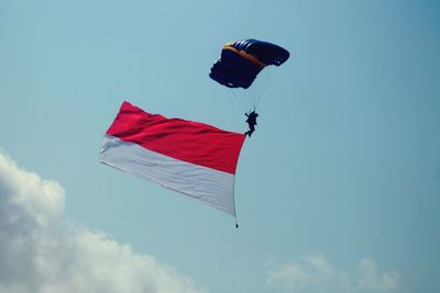 Low angle view of man on parachute with flag