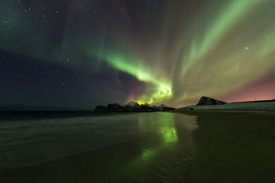 Scenic view of beach against aurora borealis at night