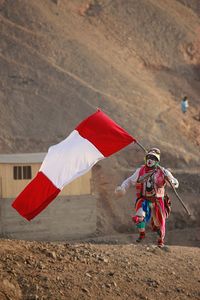 Boy flying over red umbrella against sky