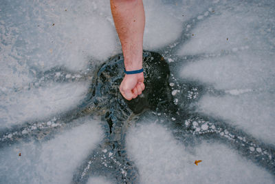 High angle view of hand on frozen ice