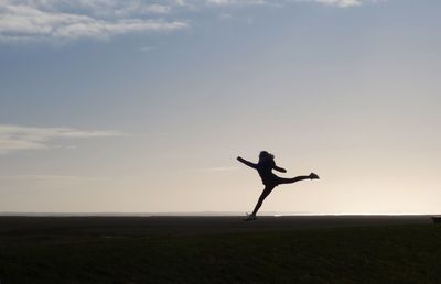 Silhouette woman doing yoga on street against sky during sunset