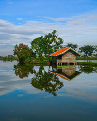 Tradisional house by lake against sky with clear reflection