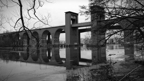 Reflection of bare trees in water against sky