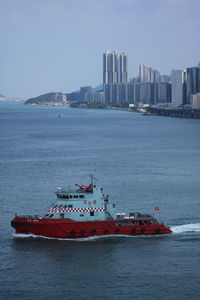 Nautical vessel on sea by buildings against clear sky