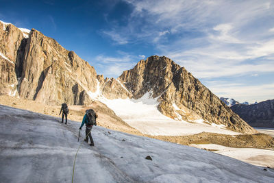 Backpackers crossing a glaciated mountain on baffin island.