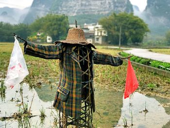Scarecrow in lake against mountains
