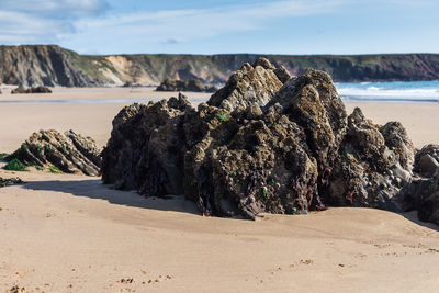Rock formation on beach against sky