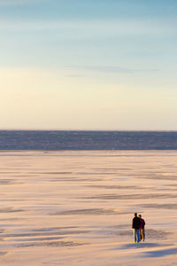 People standing on sand against sea at beach