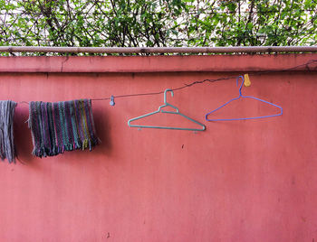 Low angle view of coathangers with fabrics on clothesline against wall