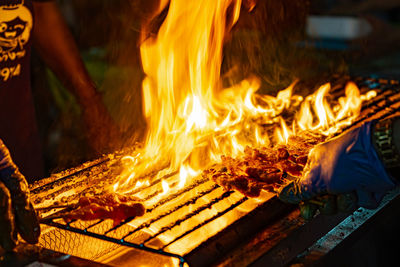 Midsection of man preparing food on fire