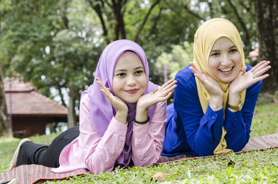 Smiling friends in hijab lying on field