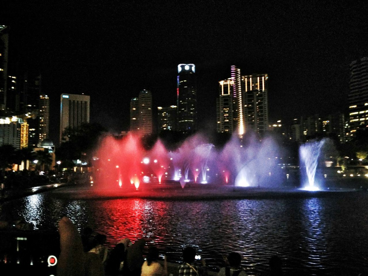 VIEW OF ILLUMINATED FOUNTAIN WITH CITY IN BACKGROUND