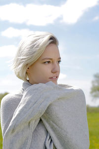 Young woman looking away against sky