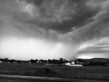 Storm clouds over agricultural field against cloudy sky