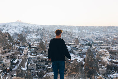 Rear view of man looking at cityscape against sky