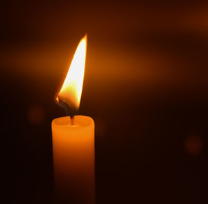 Close-up of lit candle in darkroom