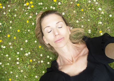 Directly above view of woman lying with eyes closed on grass