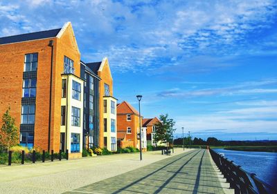 Houses by street against blue sky