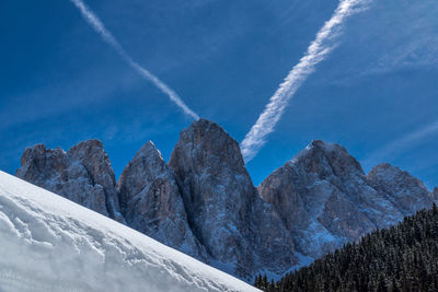 Low angle view of snowcapped mountains against blue sky