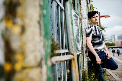 Portrait of young man standing by wall