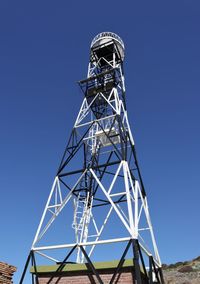 Low angle view of communications tower against clear blue sky