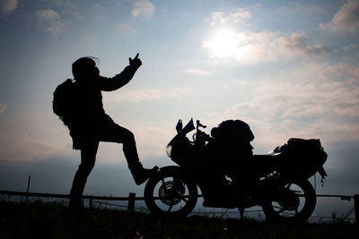 Silhouette people on motorcycle against sky during sunset