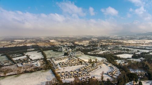 Aerial view of cityscape against cloudy sky