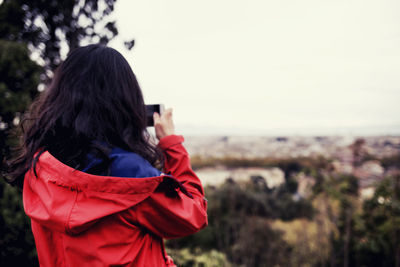 Rear view of woman photographing against sky