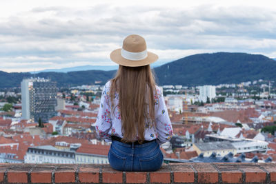 Rear view of woman standing against buildings in city