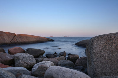 Rocks on beach against sky during sunset