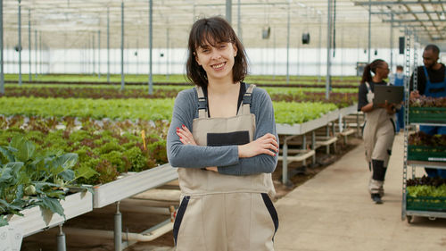 Portrait of young woman standing in greenhouse