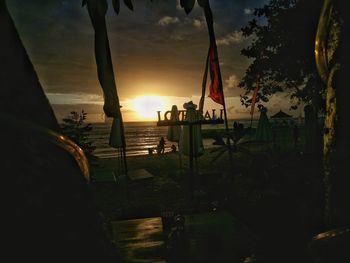 Silhouette people on beach against sky during sunset