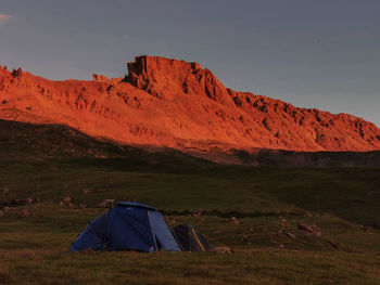 Tent on field by mountain against sky