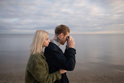 Young couple taking pictures of water in nature