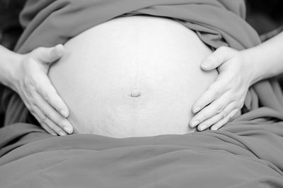 Midsection of pregnant woman with hands on stomach at home