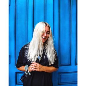 Happy woman standing against blue wall