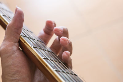 Cropped hand holding guitar fretboard