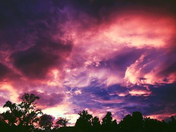 Low angle view of silhouette trees against cloudy sky