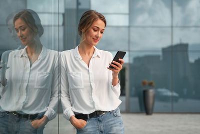 Young woman using smart phone while standing outdoors