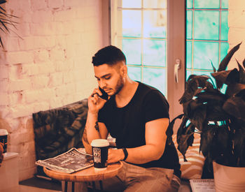 Young man using mobile phone while sitting on table