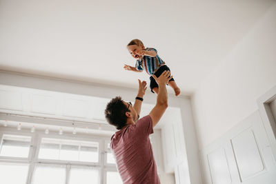 Low angle view of playful father catching son at home