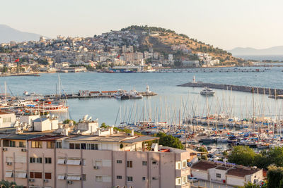 Sailboats moored in harbor by city against sky