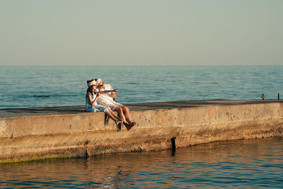 Dad and daughter in santa claus hats eat ice cream on the pier