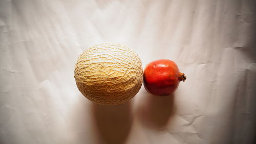 Directly above view of muskmelon and pomegranate on paper