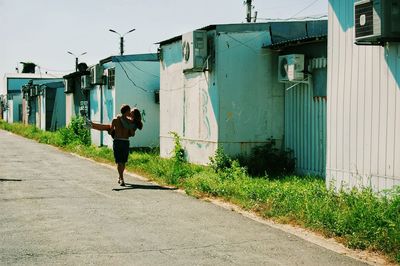 Boyfriend kissing girlfriend while carrying on road by houses