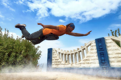 Low angle view of man jumping against built structure