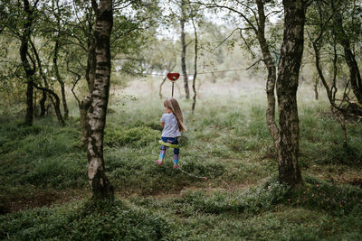 Rear view of boy standing on field in forest