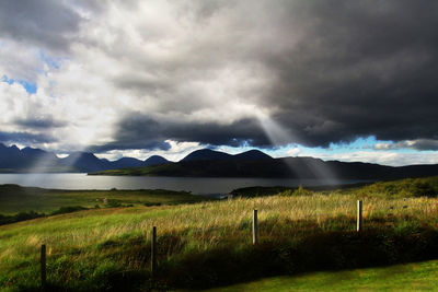 Scenic view of field against storm clouds